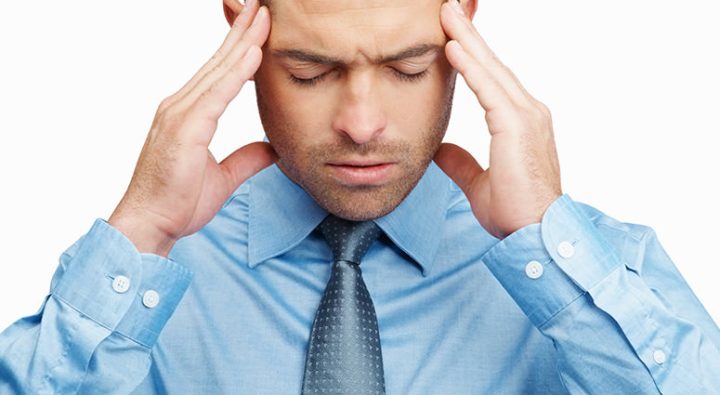 Headache - Closeup of a young business man holding head in pain isolated on white